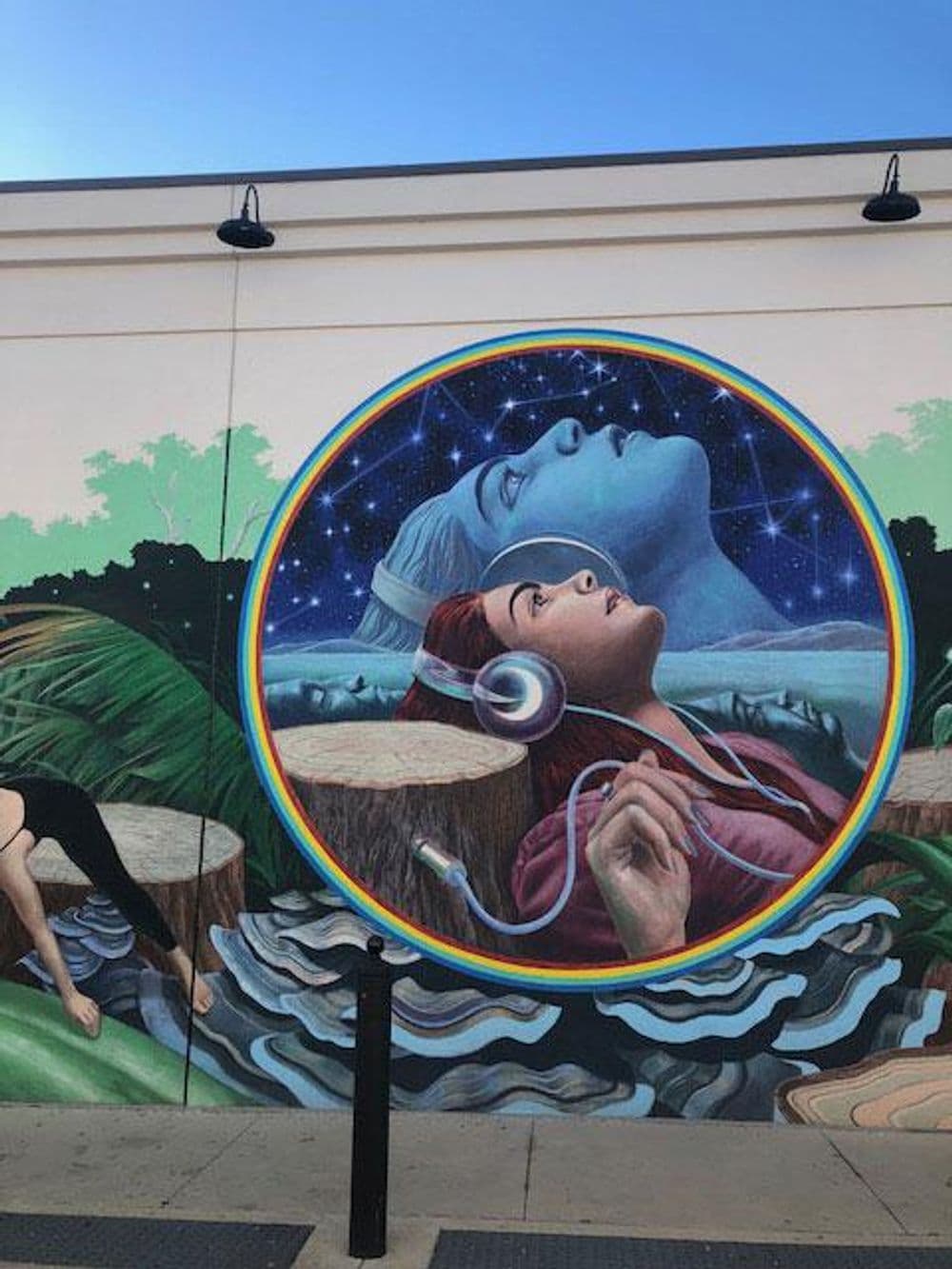 Vibrant mural featuring a woman with headphones against a cosmic backdrop and nature elements.