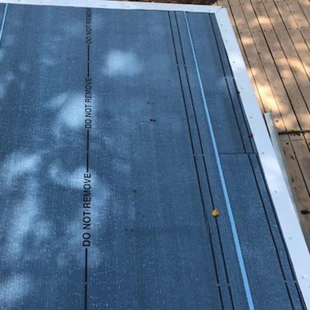 Roofing underlayment with "DO NOT REMOVE" markings, laid out on a wooden deck.