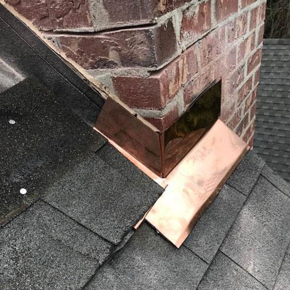 Copper flashing on a roof chimney, showing detail of installation and shingles.