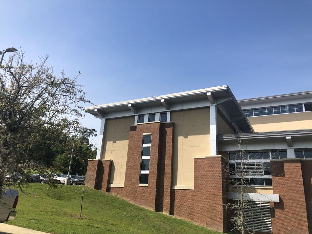 Modern educational building with a mix of brick and concrete under a clear blue sky.