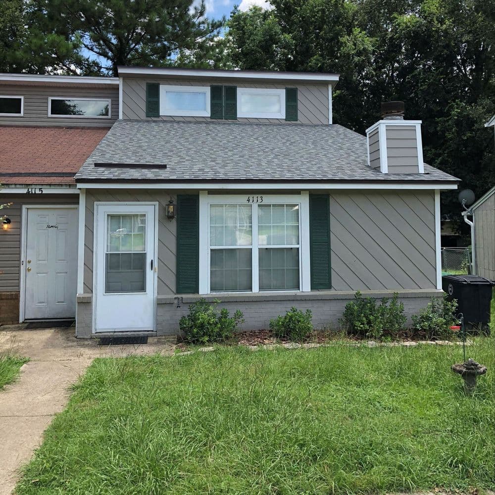 Front view of a modern two-story house with green shutters and a neatly landscaped yard.